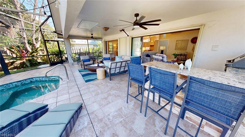 View of lanai featuring plunge pool/hot tub, 2 sun loungers, 6 person dining table, gas grill, raised bar, wine fridge