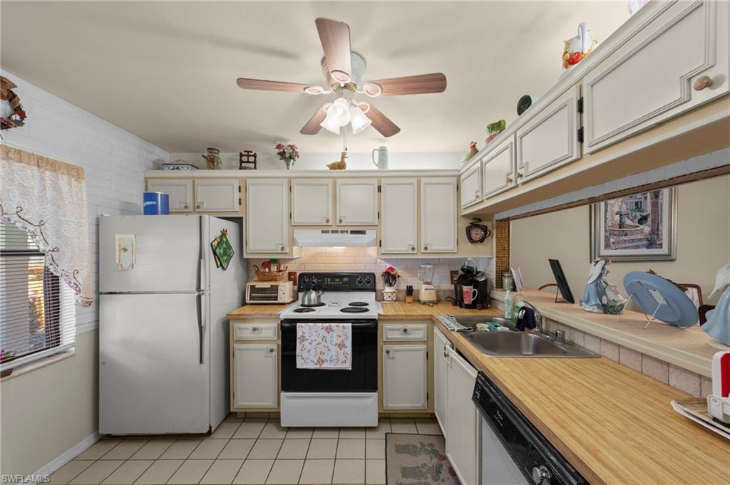 Kitchen with white appliances, light countertops, ceiling fan, light tile patterned floors, and backsplash