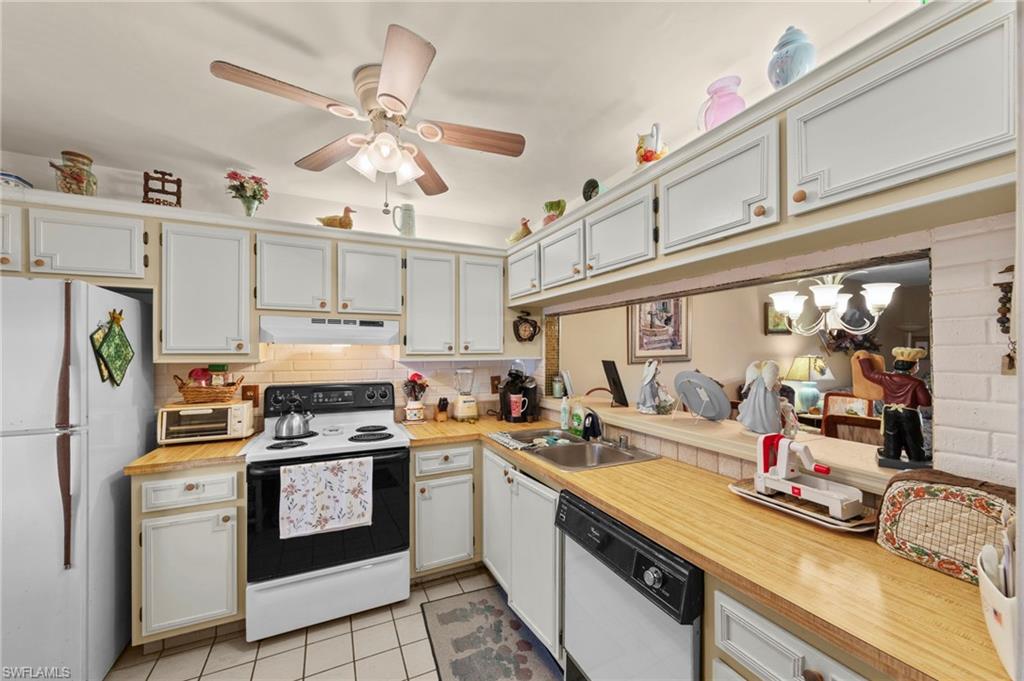 Kitchen with white appliances, light countertops, ceiling fan, and light tile patterned floors