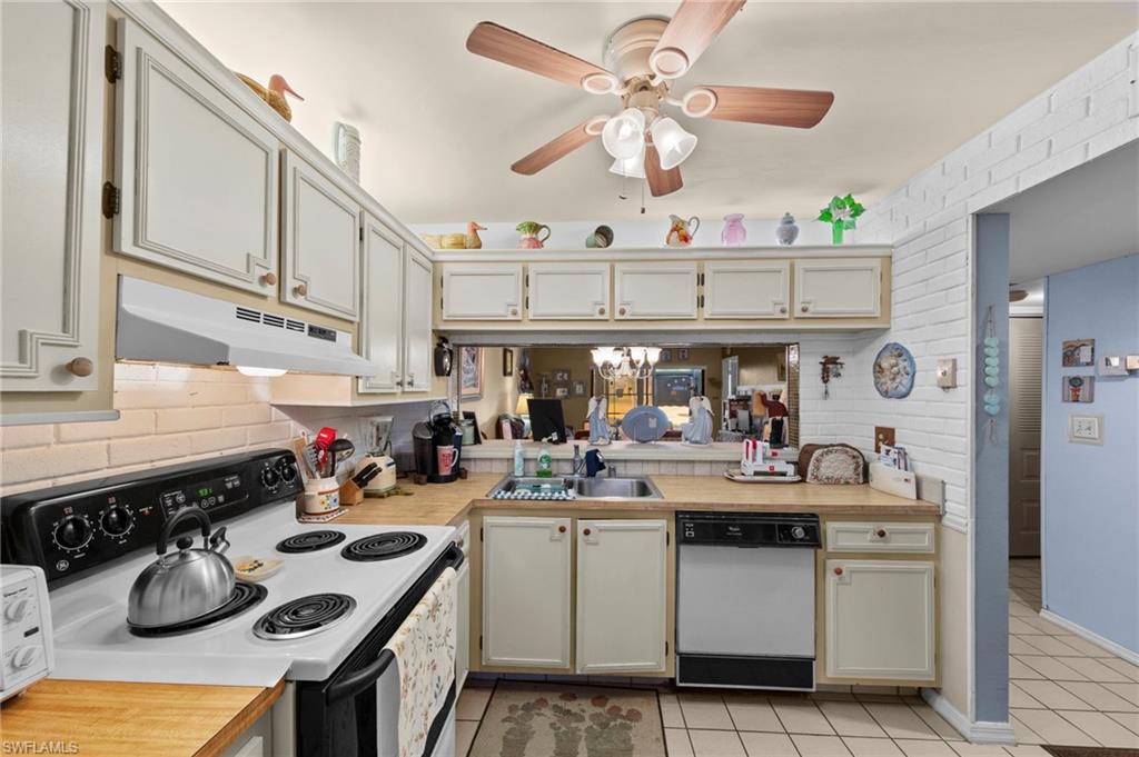Kitchen featuring electric range, light countertops, ceiling fan, white dishwasher, and light tile patterned floors