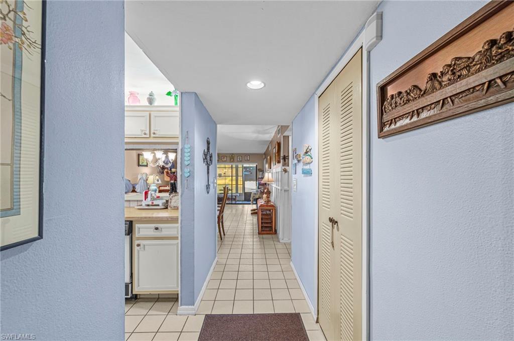 Hall with a textured wall, light tile patterned floors, and recessed lighting