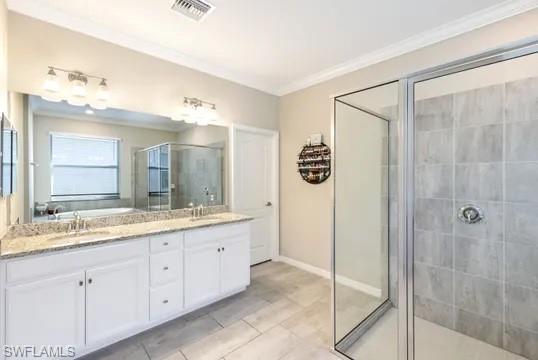 Full bathroom featuring a shower stall, double vanity, ornamental molding, and light tile patterned flooring