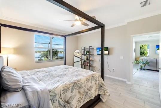 Bedroom with ceiling fan, light wood finished floors, and ornamental molding