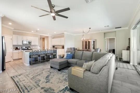 Living area featuring ornamental molding, a ceiling fan, and recessed lighting