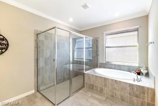 Bathroom with a stall shower, a bath, and ornamental molding