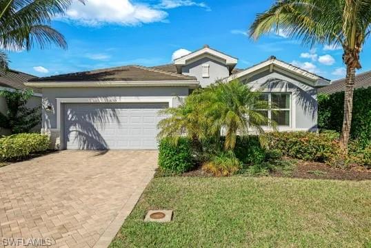 View of front of house featuring decorative driveway, a front yard, an attached garage, and stucco siding
