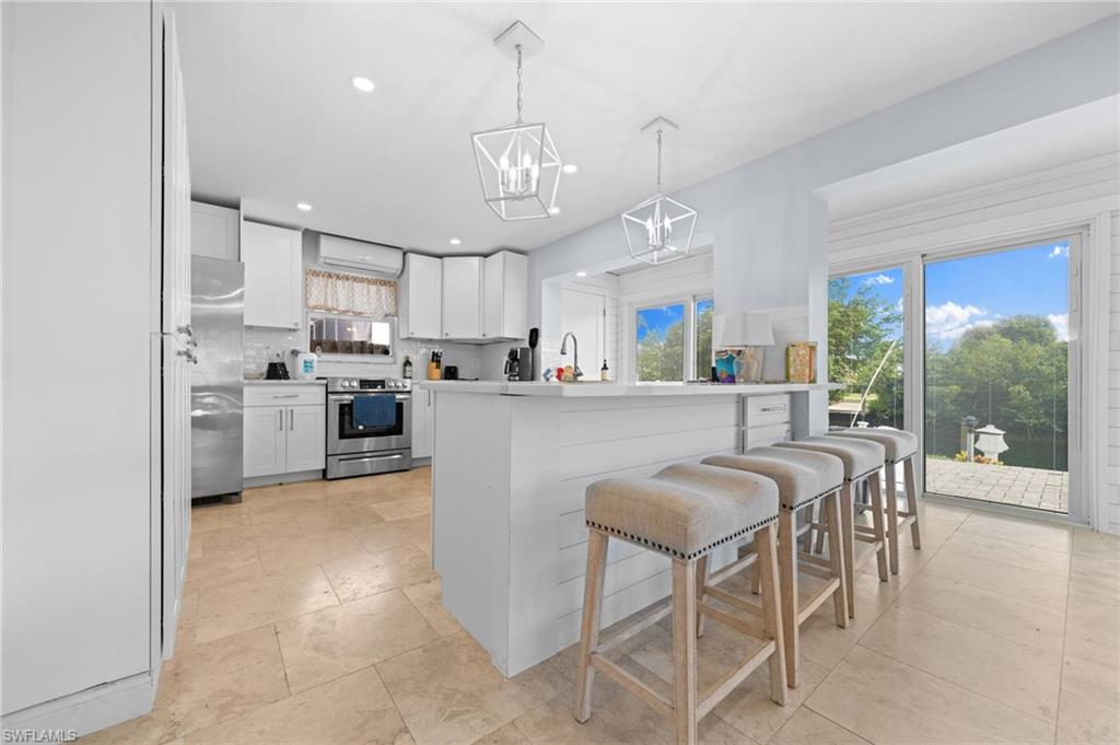 Kitchen featuring a kitchen island, pendant lighting, white cabinetry, appliances with stainless steel finishes, and backsplash