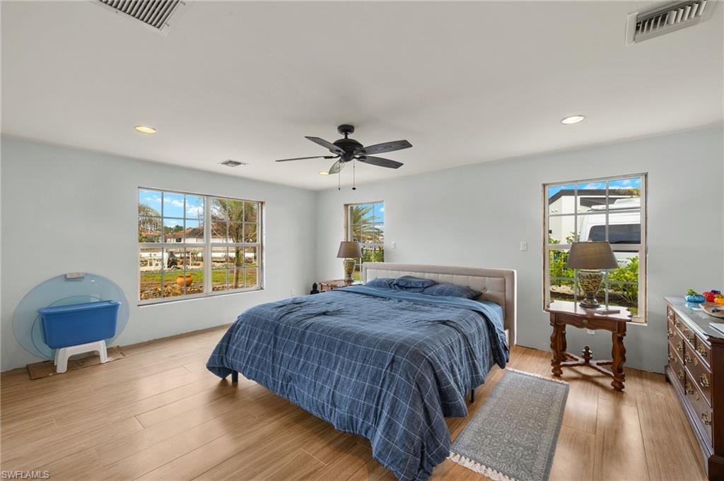 Bedroom with multiple windows, ceiling fan, and light wood-type flooring