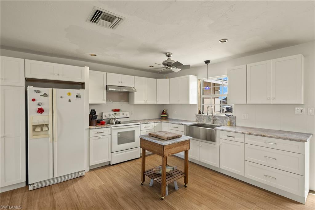 Kitchen featuring white cabinetry, white appliances, sink, and decorative light fixtures