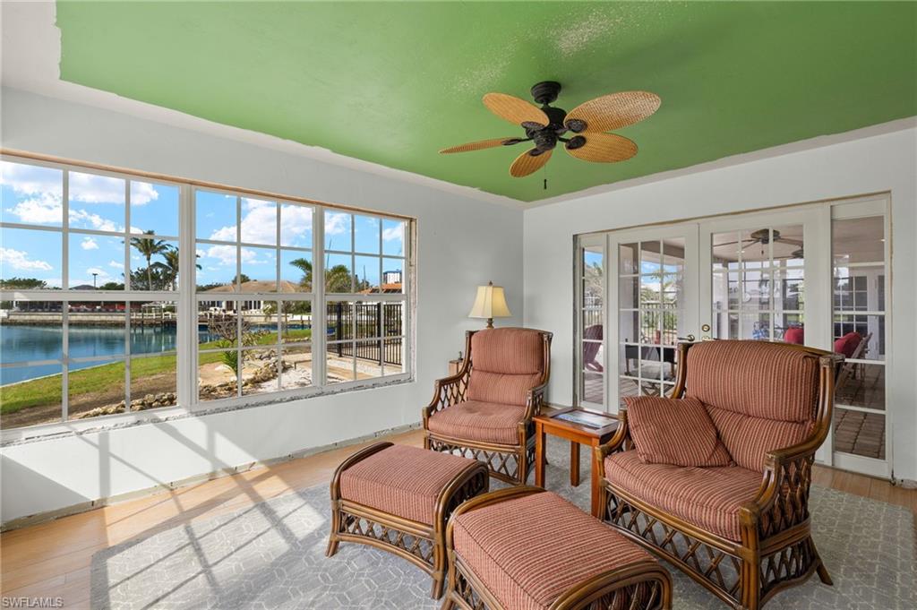 Sunroom / solarium with ceiling fan, a water view, and french doors