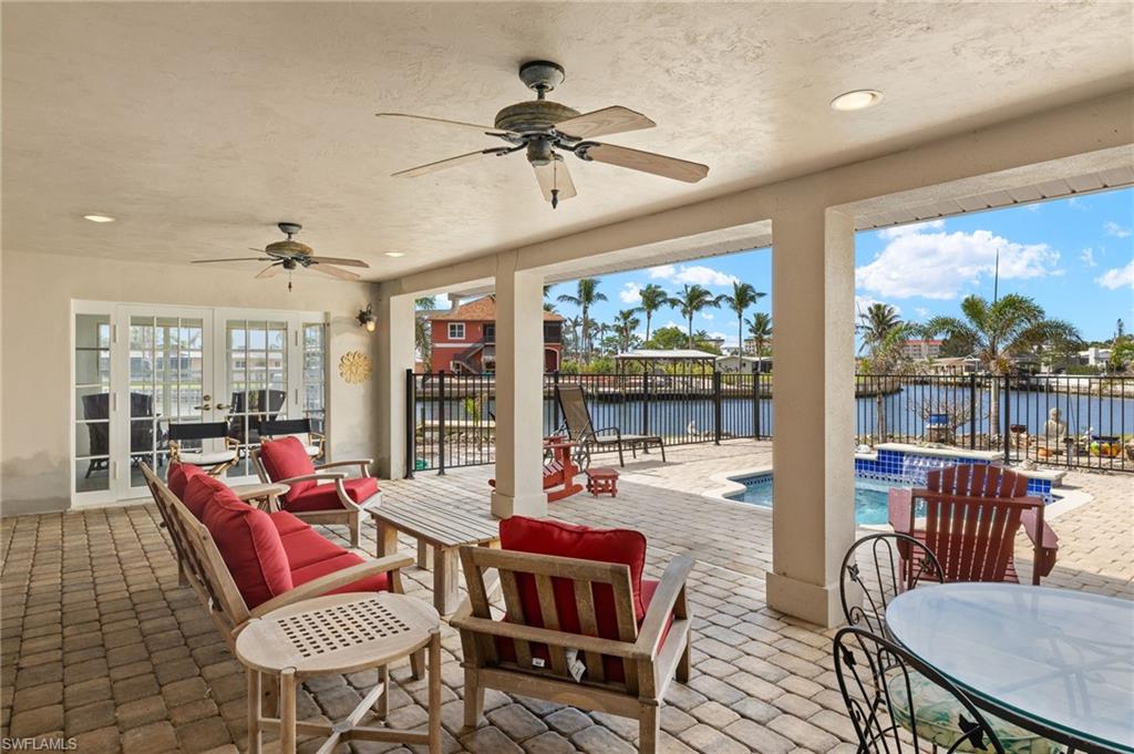View of patio with ceiling fan, french doors, a water view, and a fenced in pool virtually enhanced images