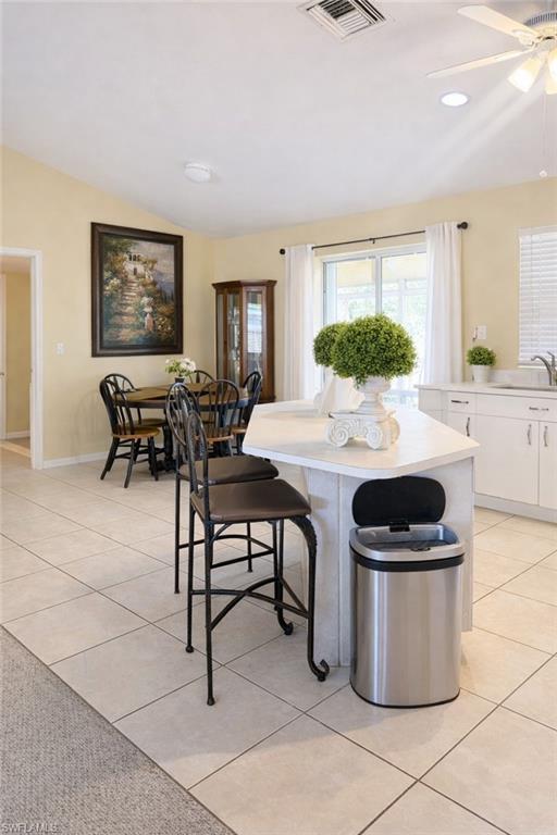 Dining space featuring lofted ceiling, light tile patterned floors, ceiling fan, and recessed lighting