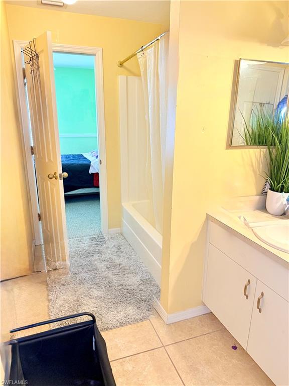 Bathroom featuring vanity, connected bathroom, shower / bath combo, and light tile patterned floors