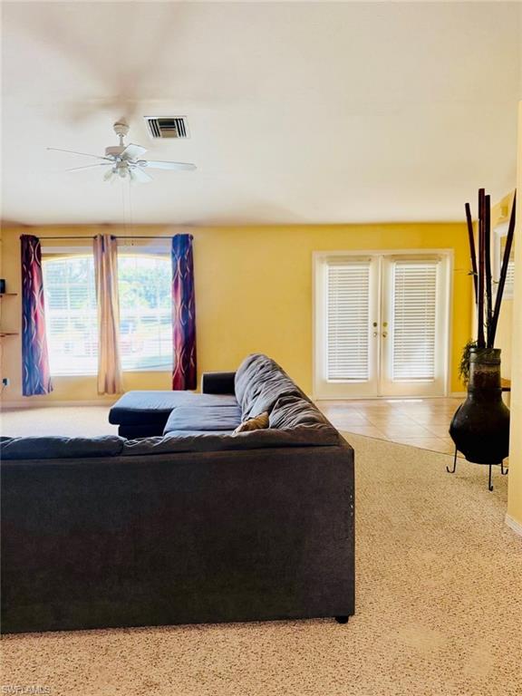 Carpeted living area with french doors and a ceiling fan