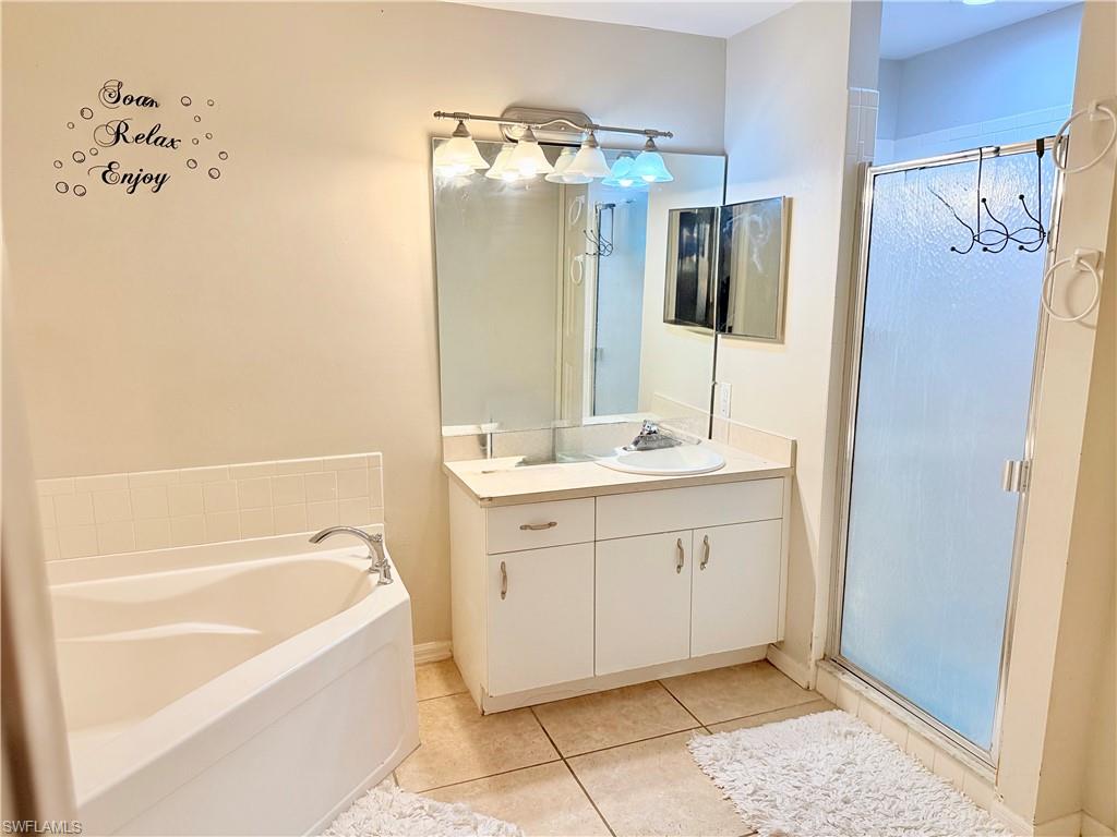 Bathroom featuring a garden tub, a shower stall, vanity, and light tile patterned floors