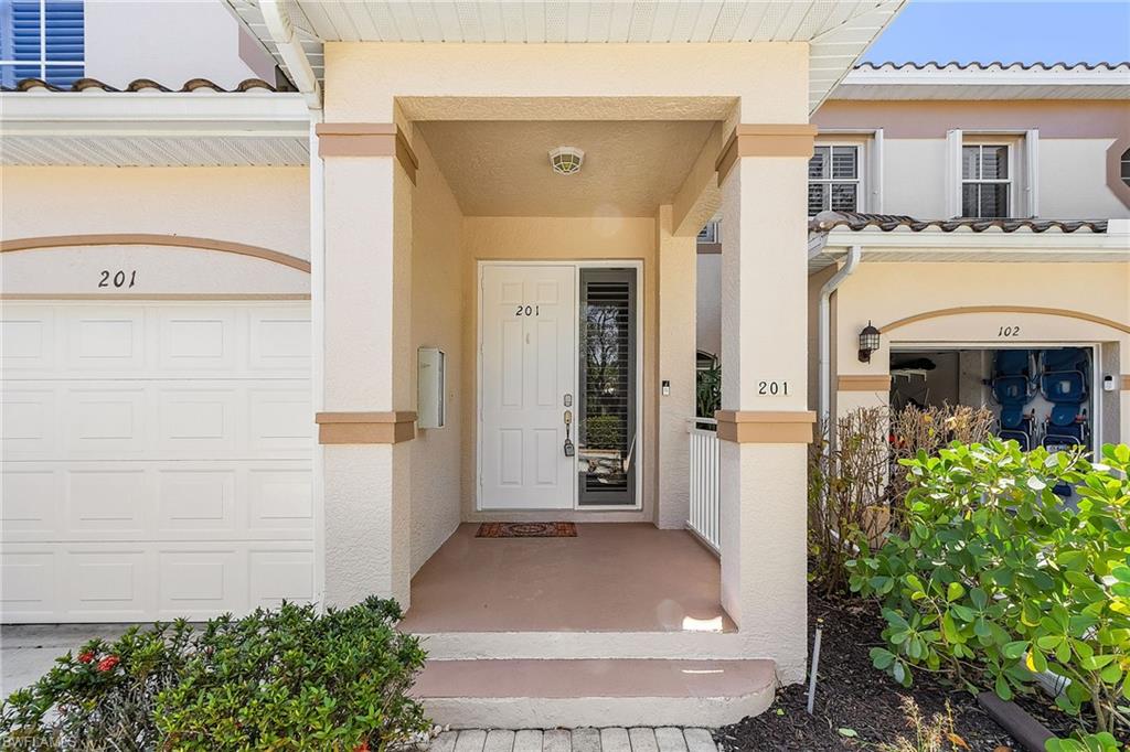Doorway to property featuring stucco siding, covered porch, and a tiled roof