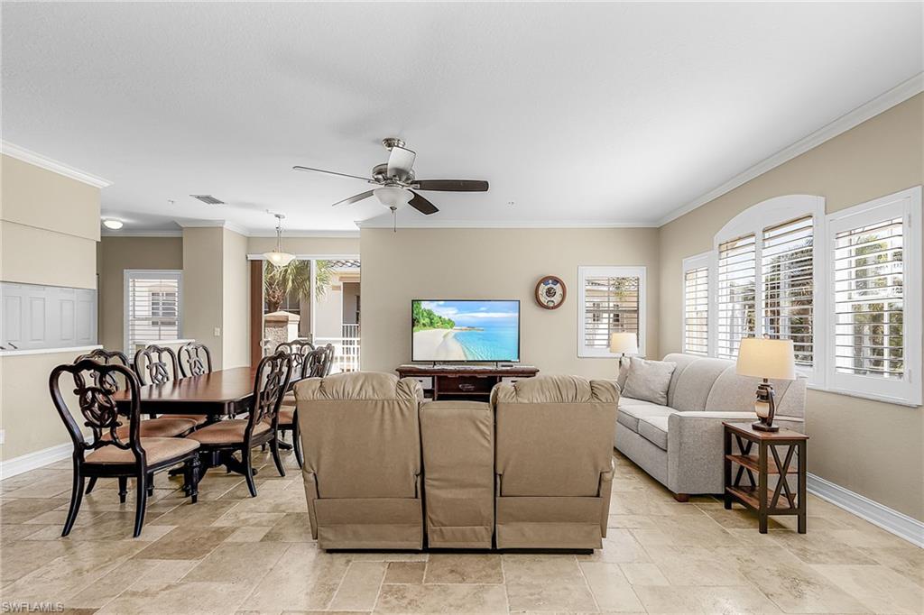 Living room featuring a ceiling fan, crown molding, and stone finish floors