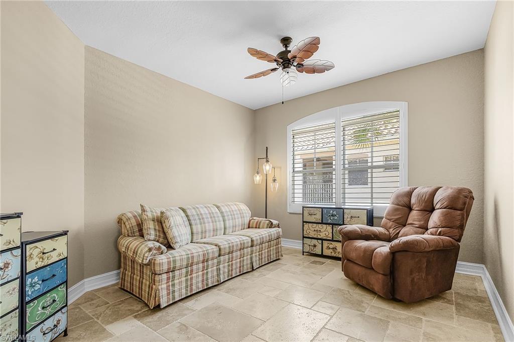 Living area featuring stone tile floors and ceiling fan