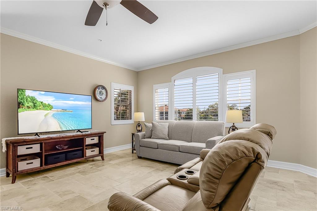Living area with ornamental molding, a ceiling fan, and stone tile flooring