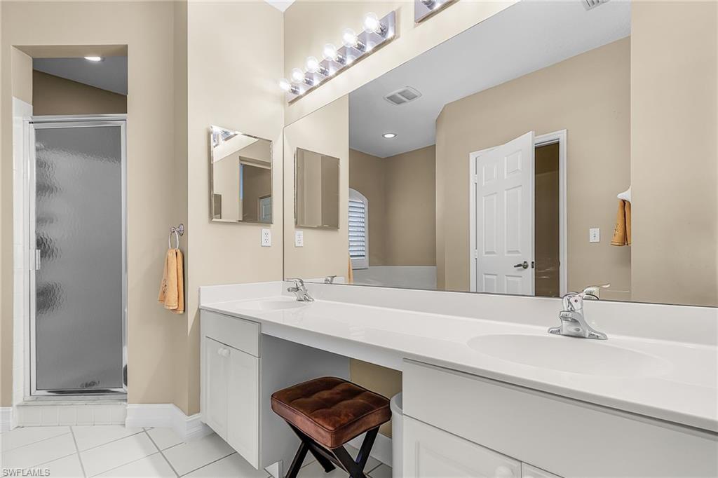 Bathroom featuring double vanity, a stall shower, and light tile patterned floors