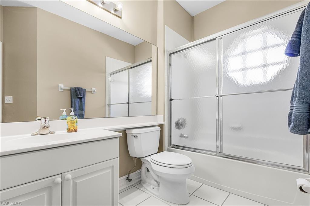 Bathroom featuring vanity, bath / shower combo with glass door, and light tile patterned flooring