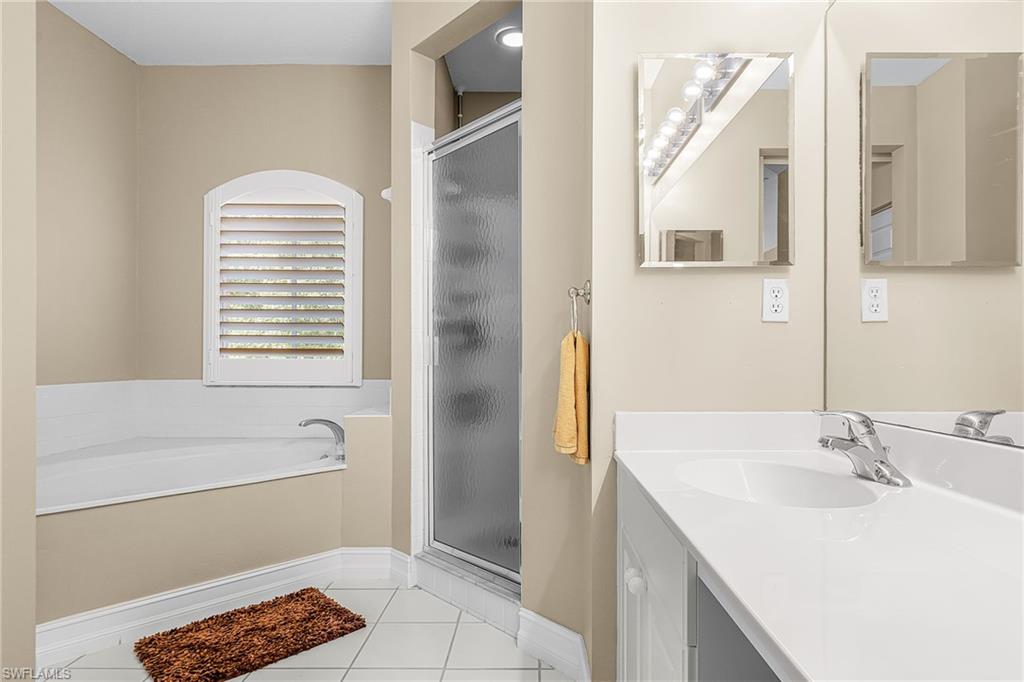 Bathroom featuring a shower stall, vanity, light tile patterned floors, and a bath