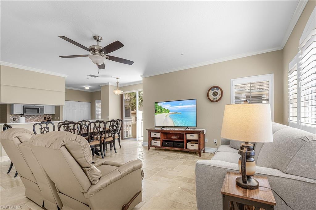 Living room with ornamental molding, stone tile floors, and ceiling fan