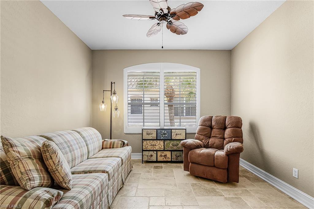 Living room with stone tile flooring, ceiling fan, and a textured wall