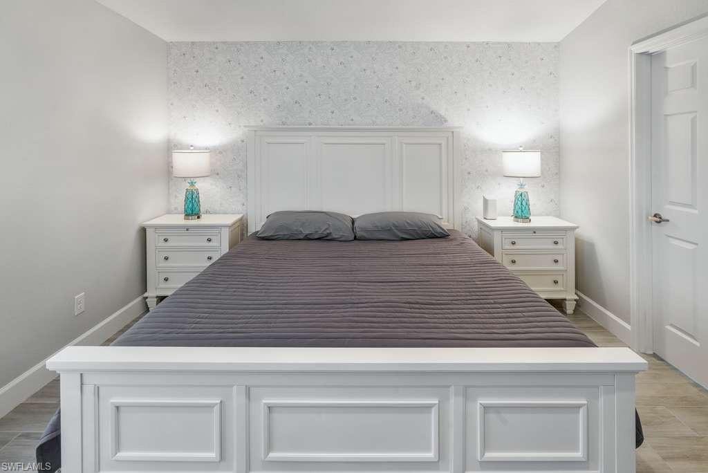 Bedroom featuring an accent wall, wallpapered walls, and light wood-type flooring