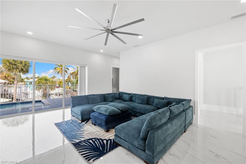 Living room featuring ceiling fan, recessed lighting, and light marble finish floors