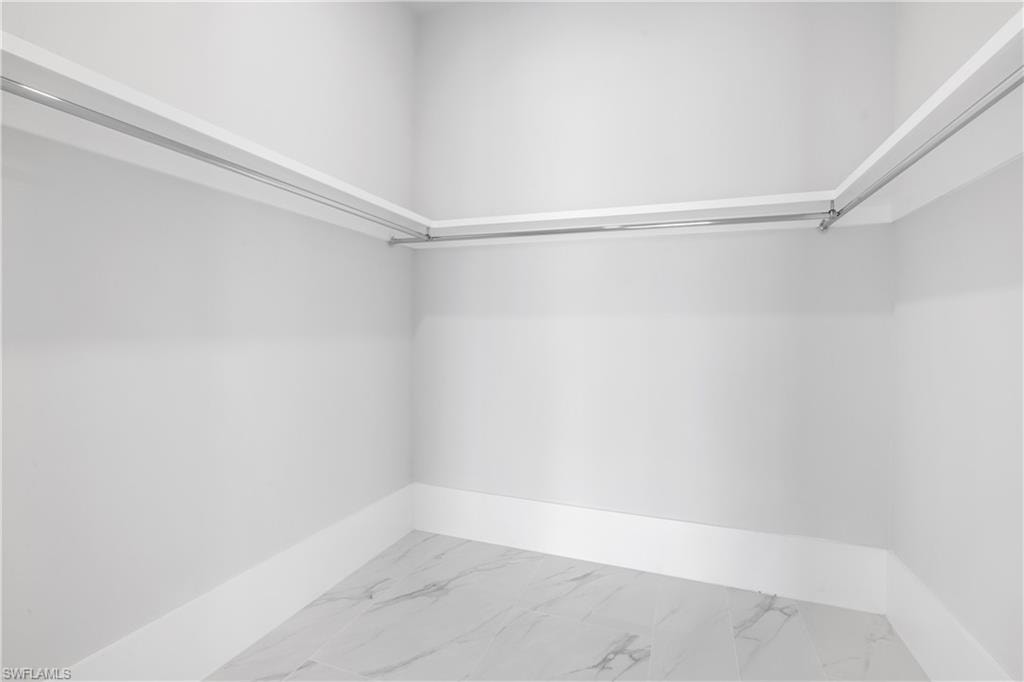 Walk in closet featuring light marble finish floors