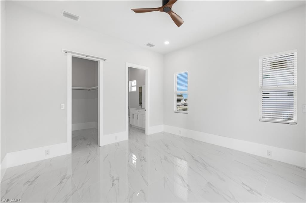 Unfurnished bedroom with a spacious closet, ceiling fan, recessed lighting, and ensuite bathroom