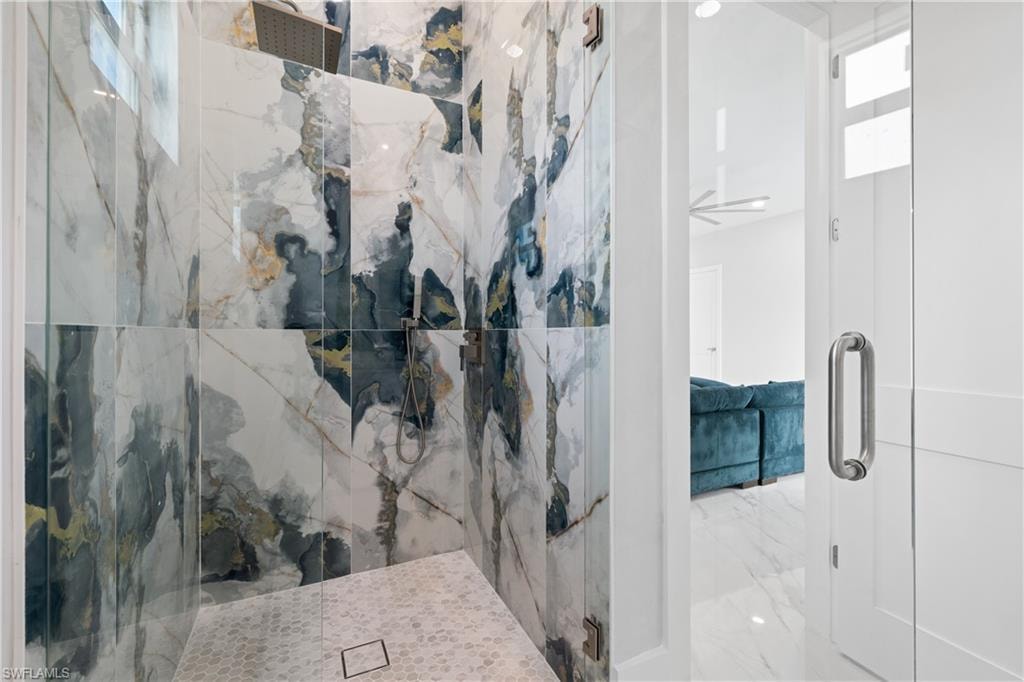 Bathroom featuring a marble finish shower and light marble finish floors