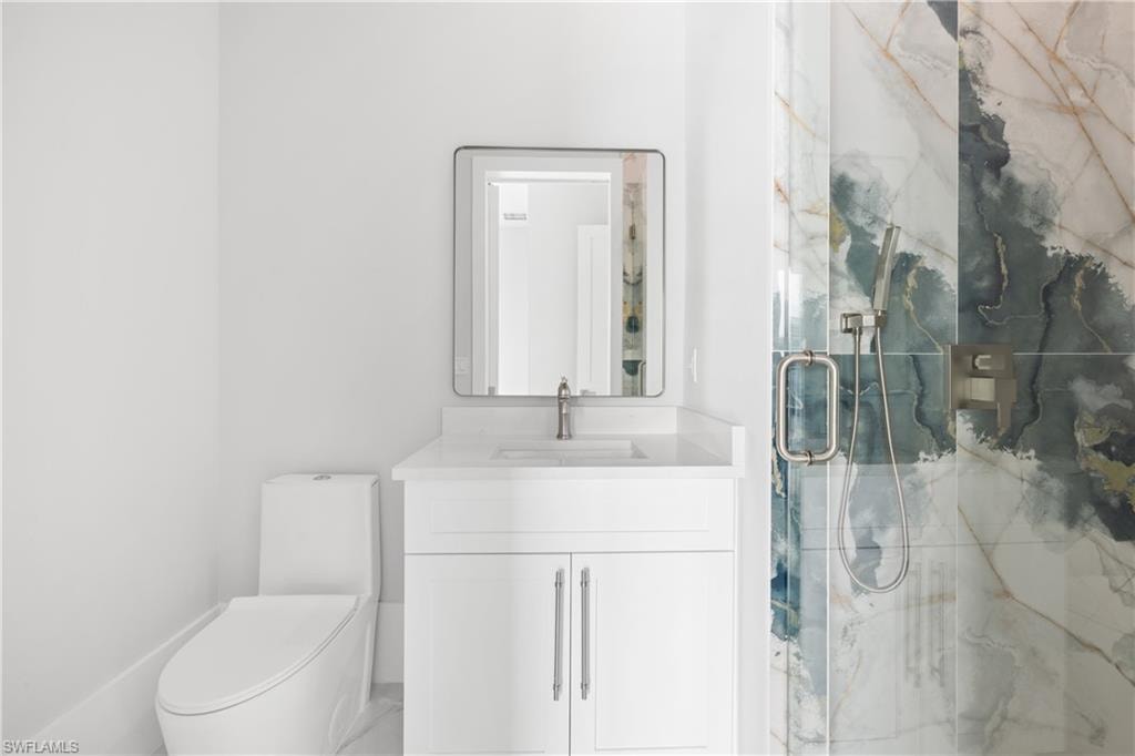 Full bathroom featuring a marble finish shower and vanity