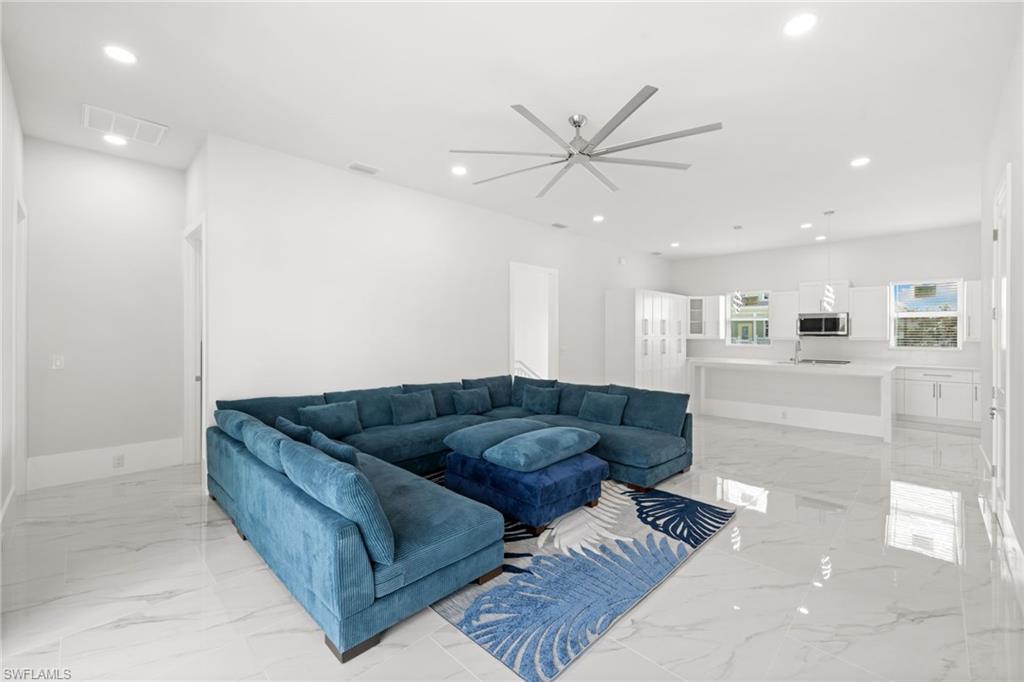 Living area with ceiling fan, recessed lighting, and light marble finish flooring