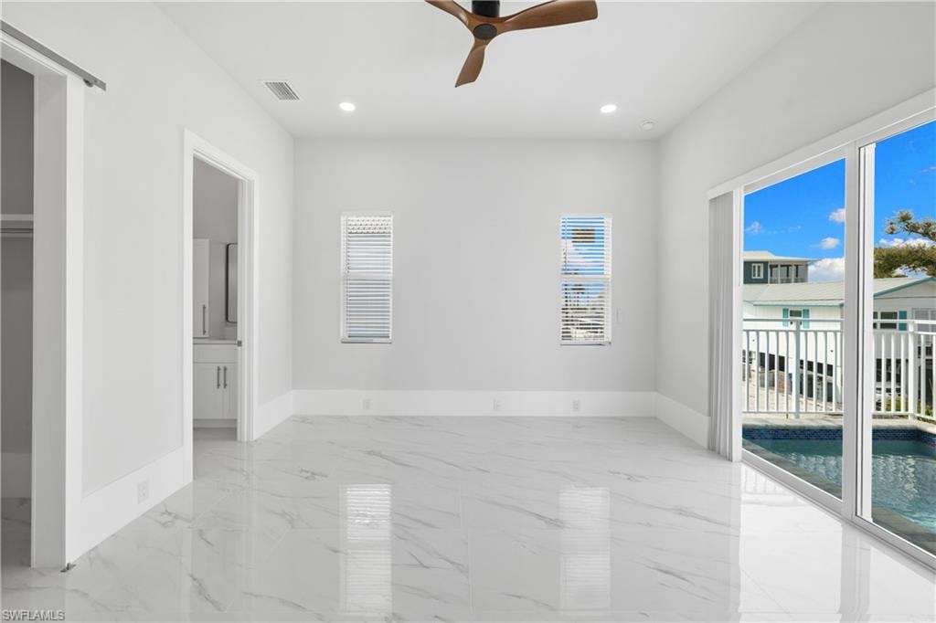 Unfurnished bedroom featuring access to outside, recessed lighting, ceiling fan, light marble finish flooring, and ensuite bath