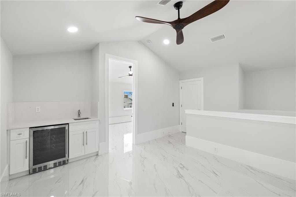 Indoor wet bar featuring wine cooler, white cabinets, a ceiling fan, recessed lighting, and light stone counters