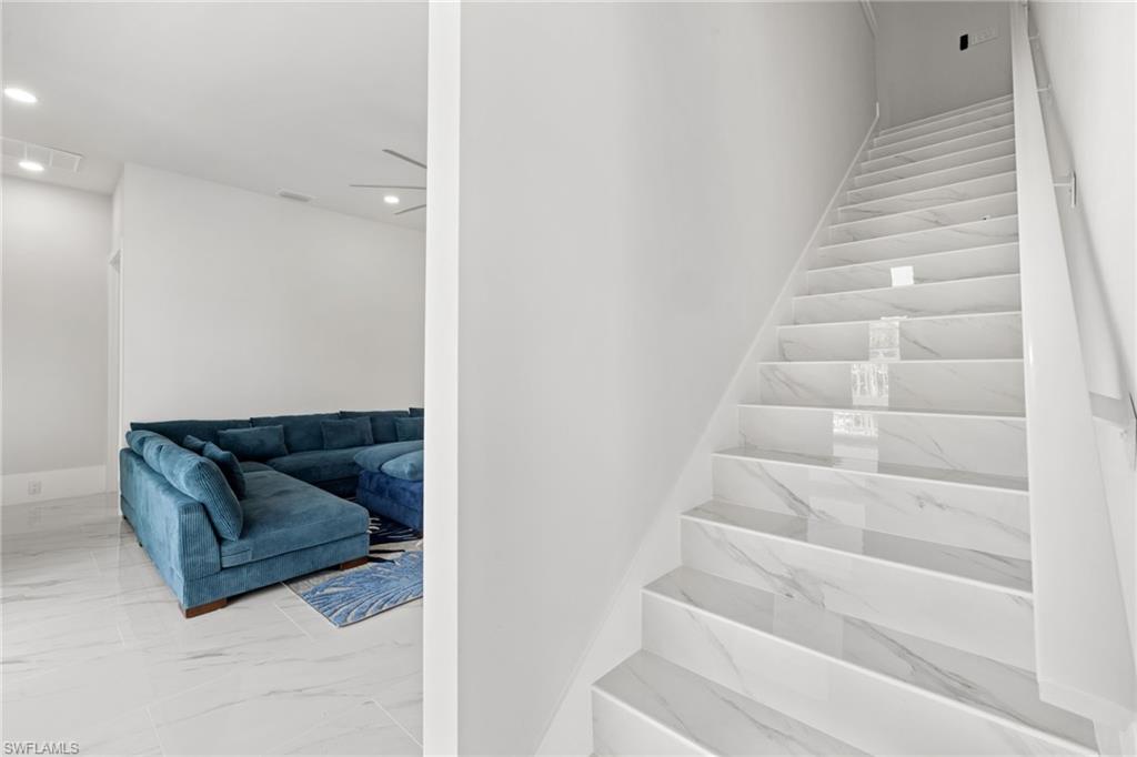Stairs featuring marble look tiles and recessed lighting