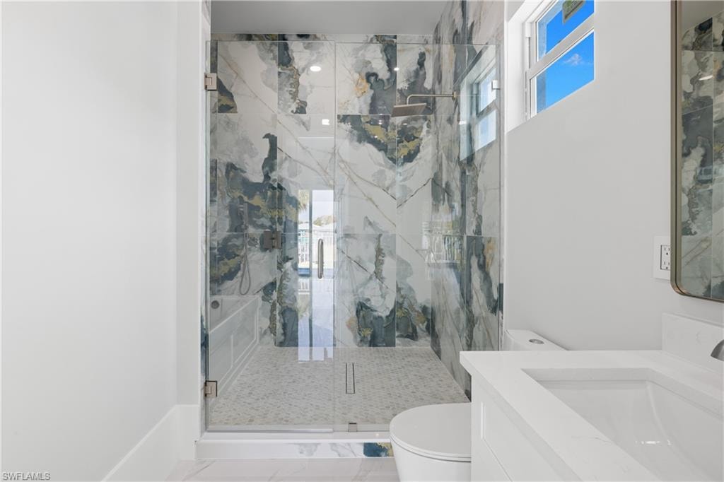 Full bath featuring a marble finish shower, plenty of natural light, and vanity