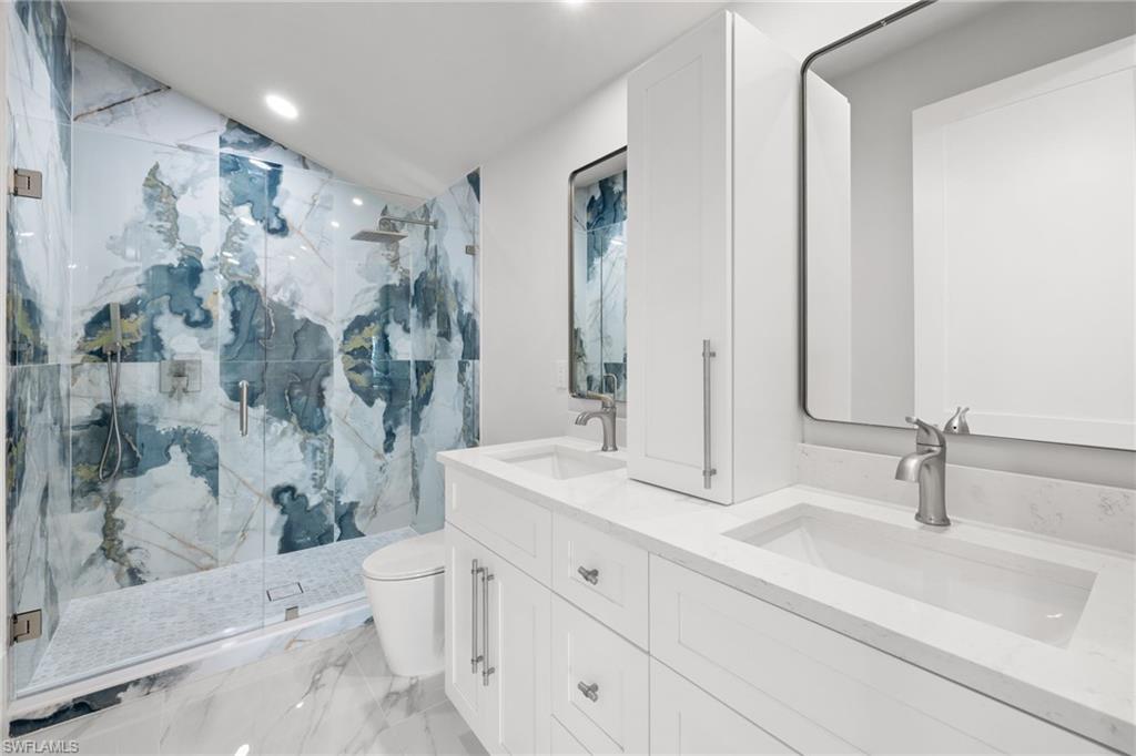 Full bathroom featuring double vanity, a marble finish shower, recessed lighting, and light marble finish floors