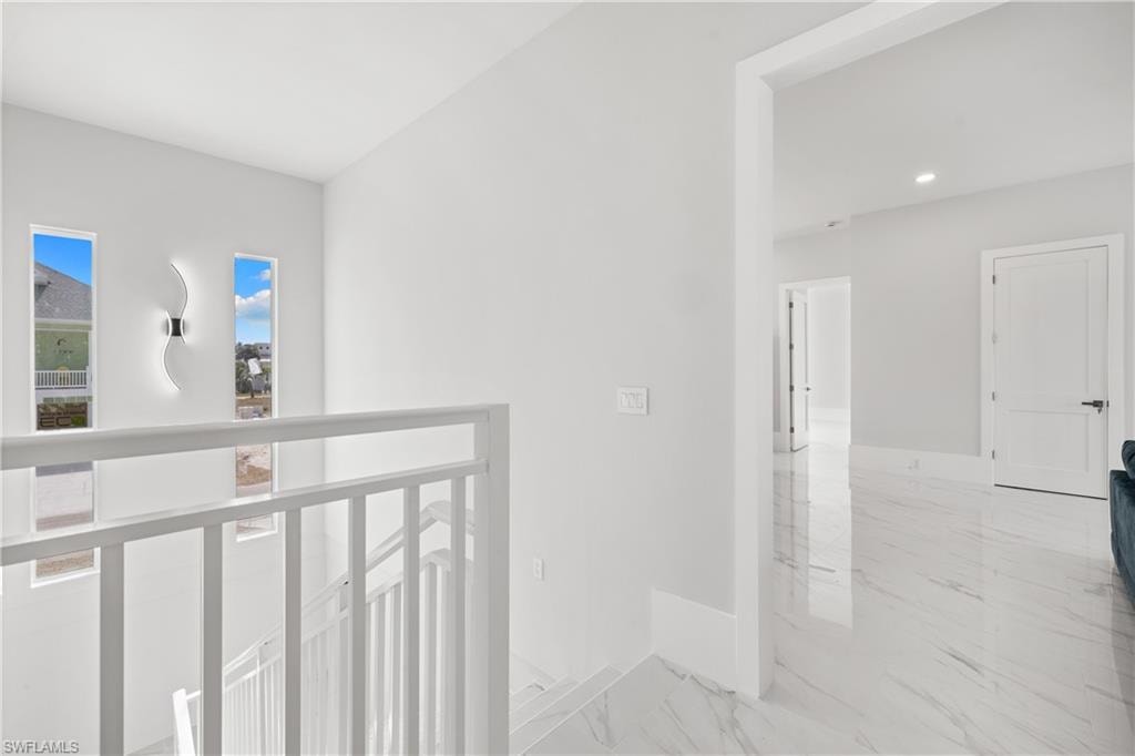 Hallway with baseboards and light marble finish floors