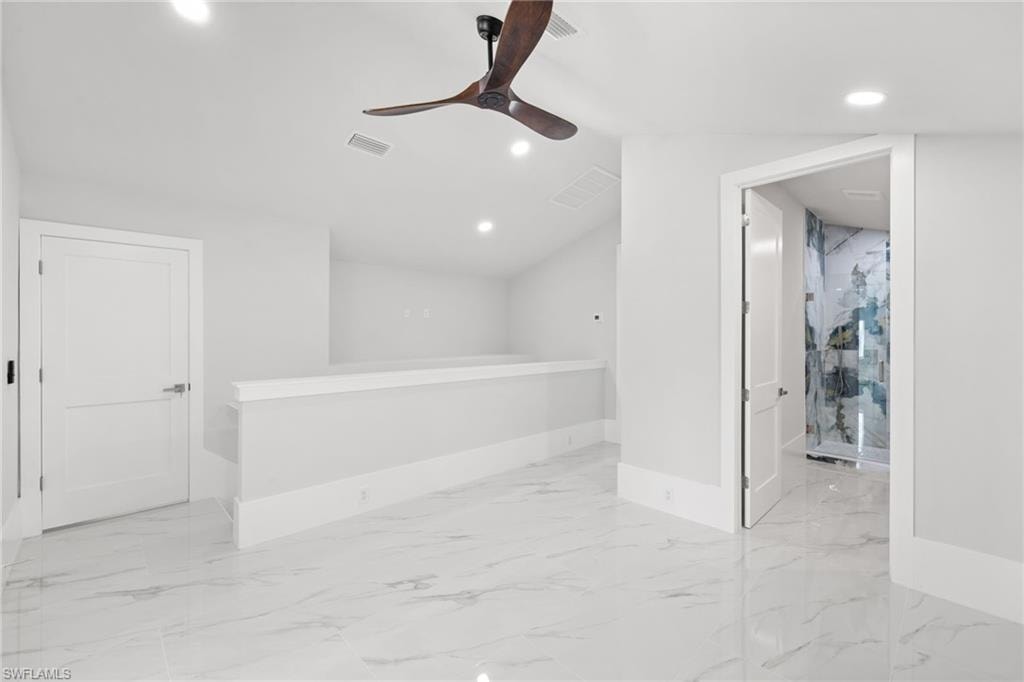 Empty room featuring recessed lighting, a ceiling fan, lofted ceiling, and light marble finish flooring