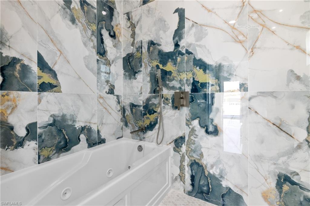 Bathroom with a tub with jets and a marble finish shower