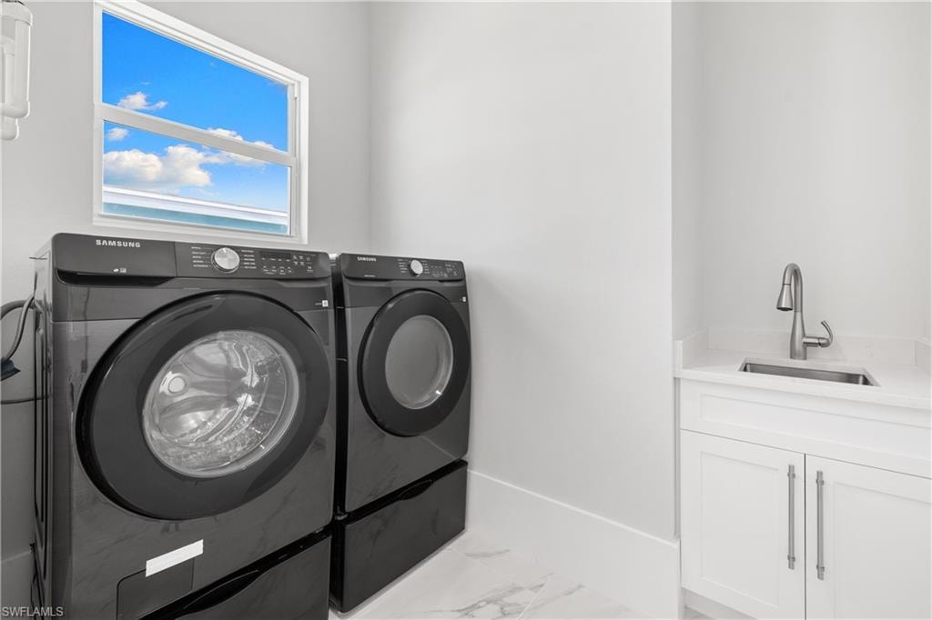 Laundry room with separate washer and dryer, cabinet space, and light marble finish flooring