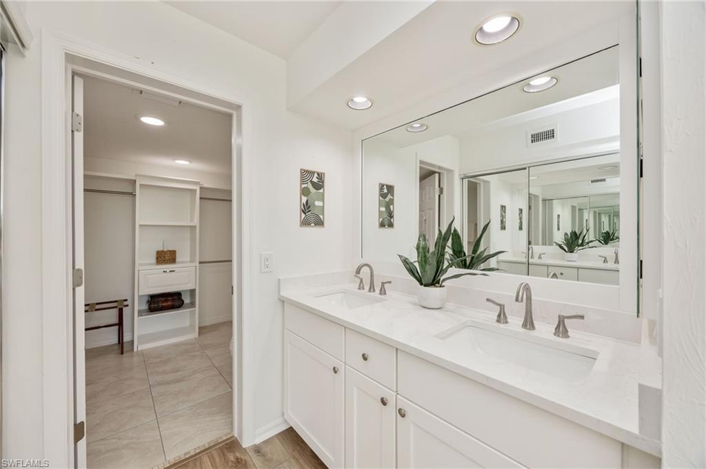 Primary Bathroom featuring recessed lighting, double vanity, light wood-style floors, and a walk in closet