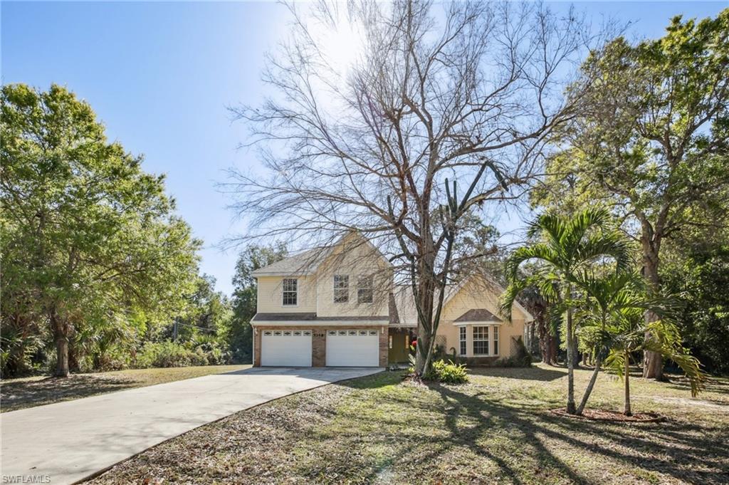 View of front of home with an attached garage and long concrete driveway