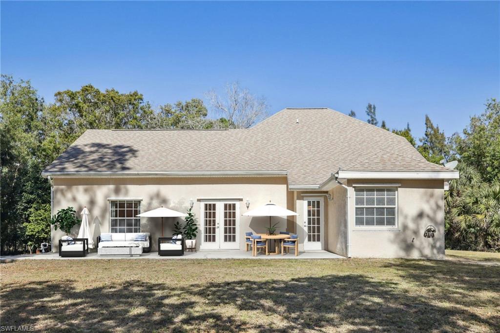 VIRTUALLY Staged Back of house with French doors, stucco siding, lawn, roof with shingles, and a patio