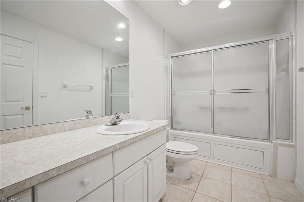 Bathroom featuring bath/shower combo with glass door, vanity, recessed lighting, and light tile patterned floors
