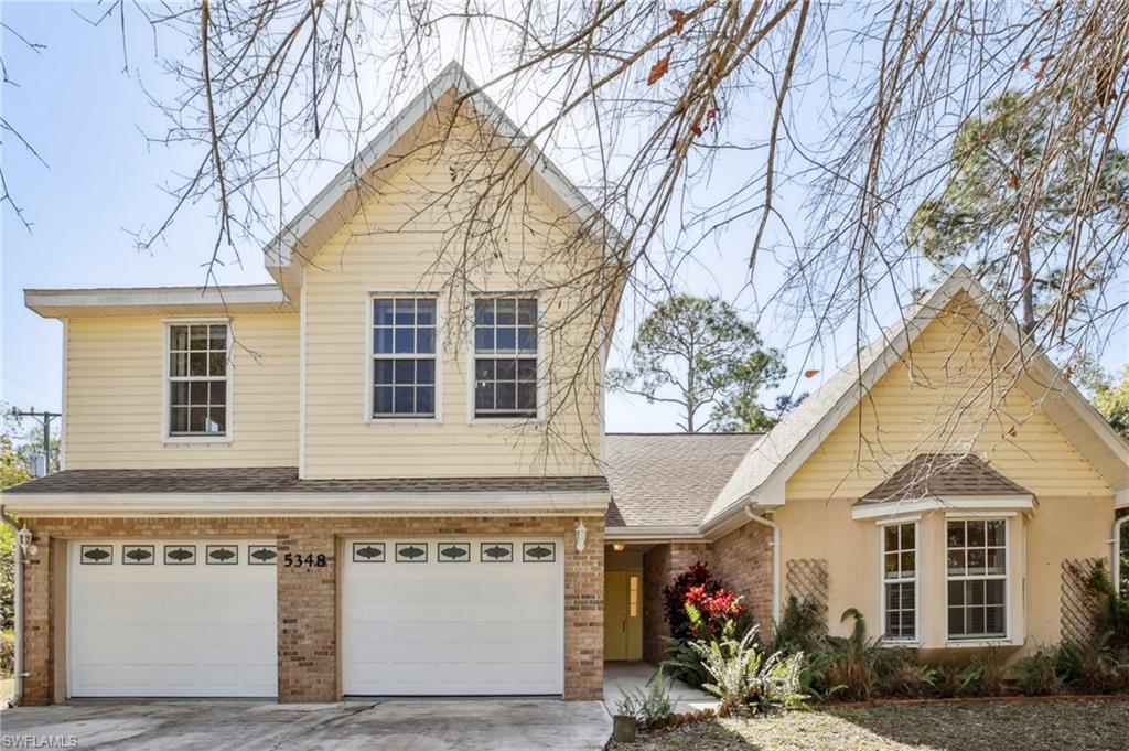 View of front of home featuring brick siding, a garage, a shingled roof, and driveway