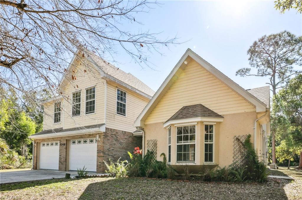 View of front of home featuring an attached garage, brick siding, driveway, stucco siding, and a shingled roof